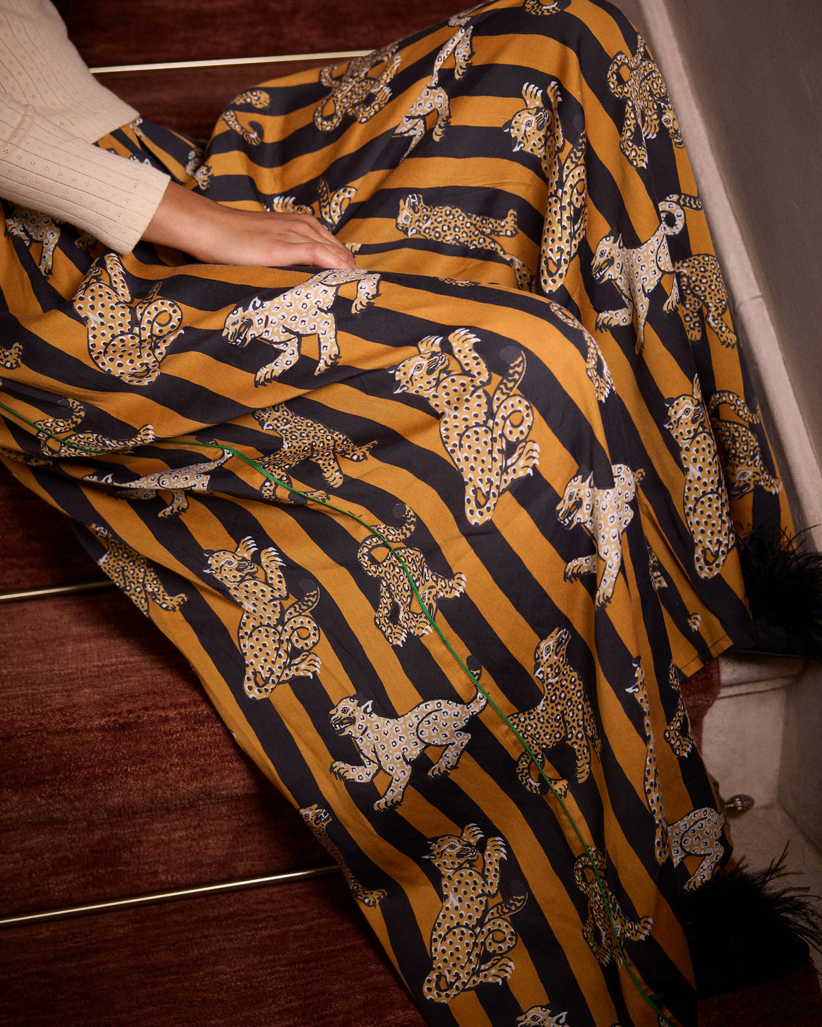 Close-up of the Leopard Stripes Tribeca pants, showing mustard and black vertical stripes with repeated leopard motifs and a green line detail.