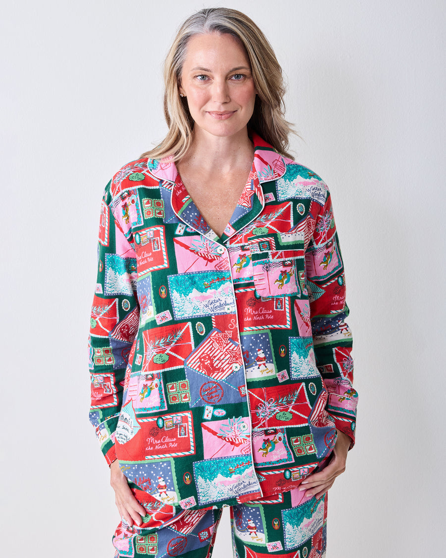 Front upper-body view of the Letters to Santa long pajama set, showing the notched collar, button front, chest pocket, and postcard print.