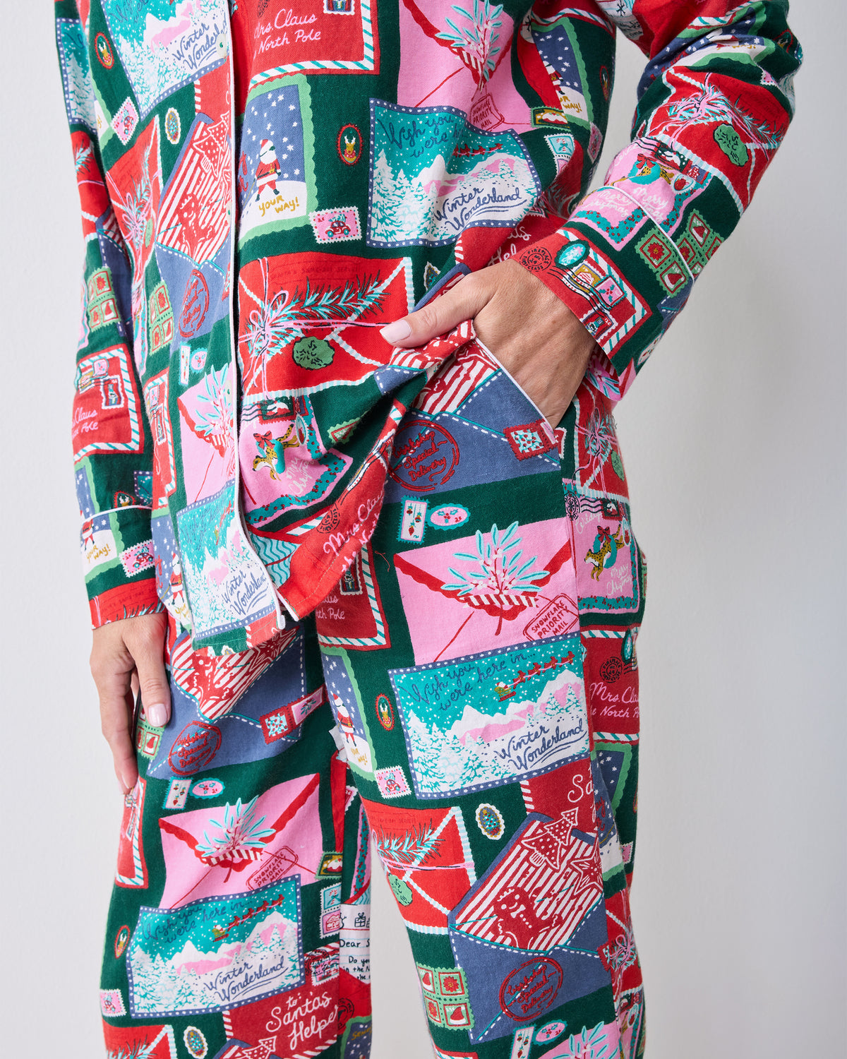 Side detail of the Letters to Santa long pajama set showing the shirt hem, sleeve cuff, side pocket, and matching printed pants.