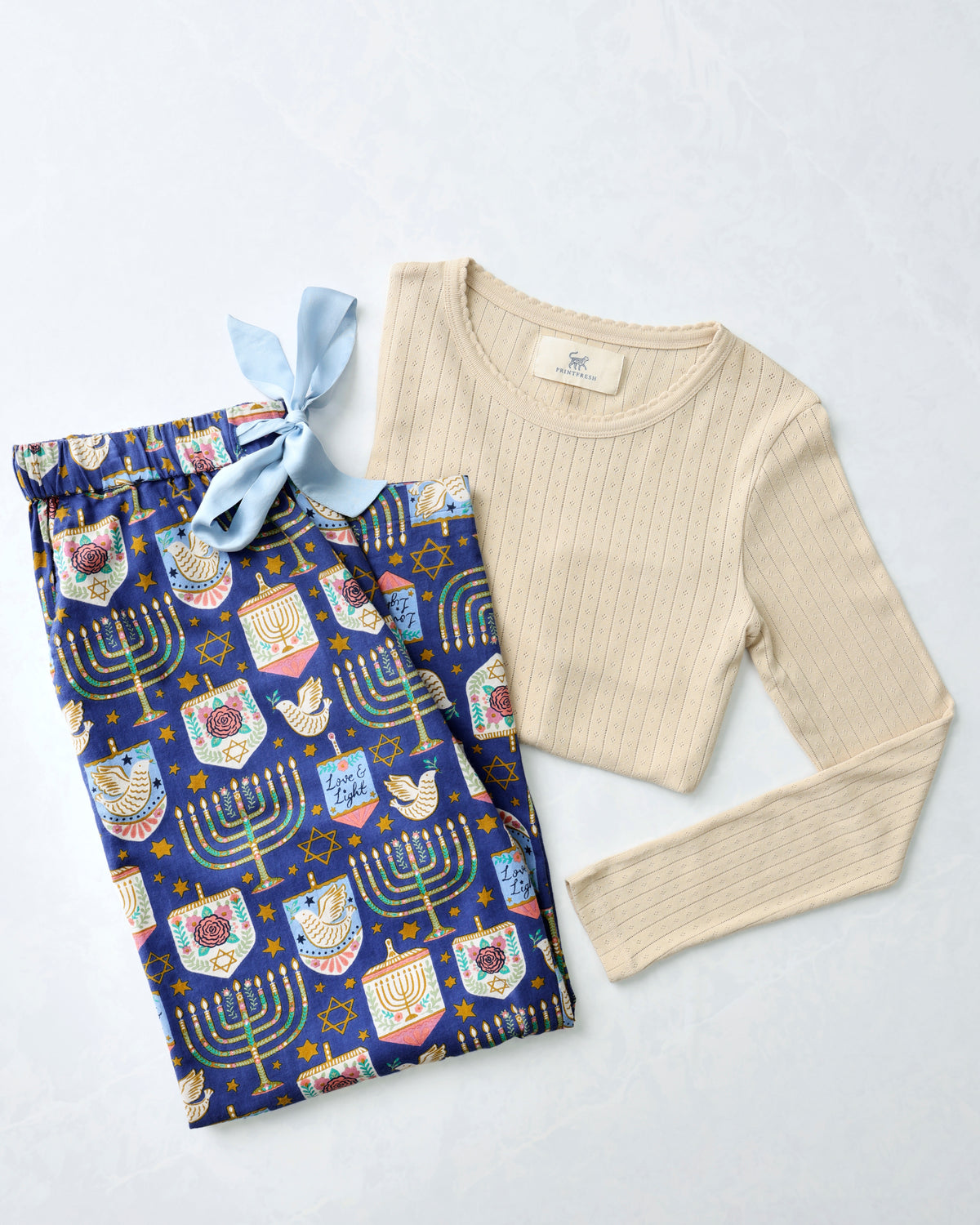 Love & Light pajama bundle with blue Hanukkah-themed pants and a cream long-sleeve pointelle top.