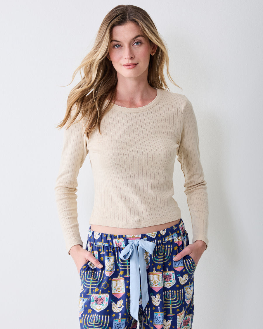 Front view of Hanukkah Blue Astrid pajama pants worn with a cream long-sleeve top, showing the wide legs and patterned drawstring waist.