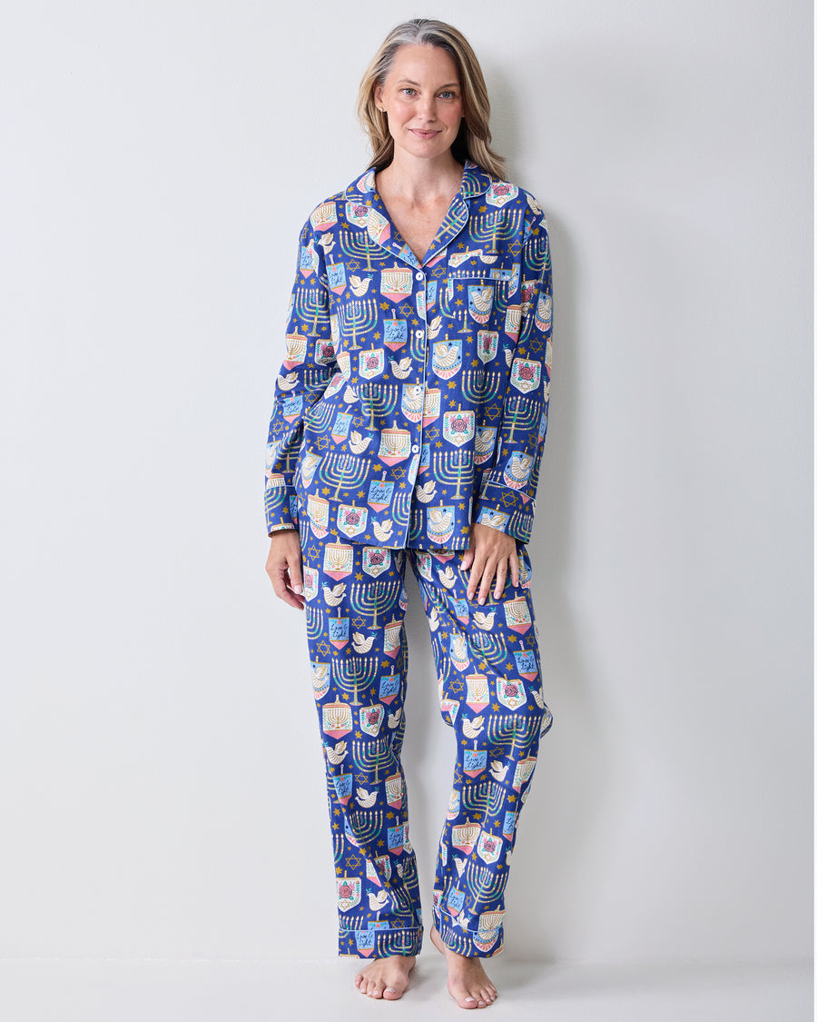 Full front view of a person wearing a blue long-sleeve collared pajama top with matching pants and a Hanukkah print.
