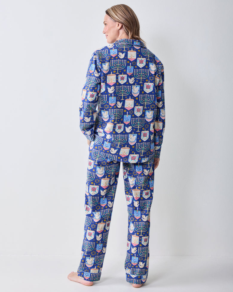 Back view of a person wearing a blue long-sleeve pajama set with a matching Hanukkah print on the top and pants.