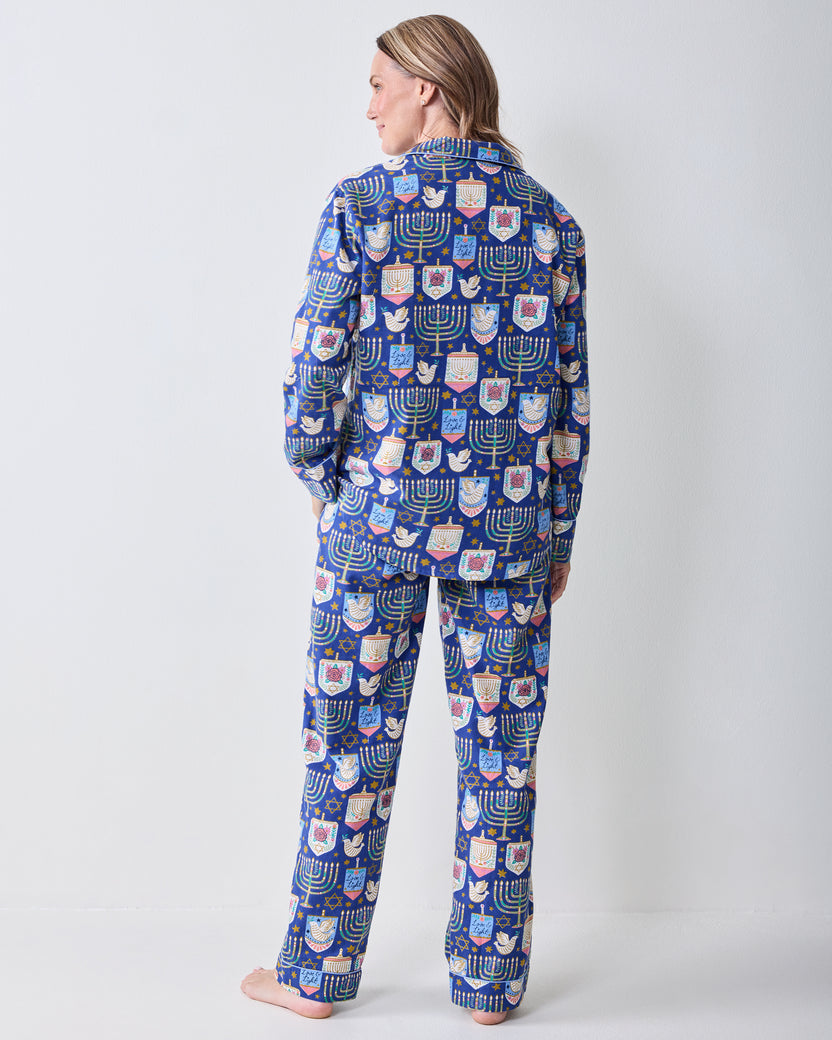 Back view of a person wearing a blue long-sleeve pajama set with a matching Hanukkah print on the top and pants.