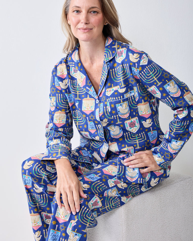 Front view of a person wearing a blue long-sleeve pajama set with a Hanukkah print, including a collared button-front top and matching pants.