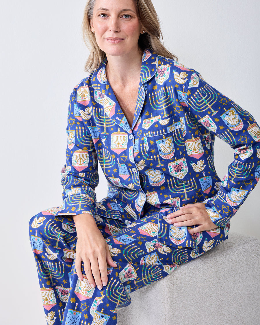 Front view of a person wearing a blue long-sleeve pajama set with a Hanukkah print, including a collared button-front top and matching pants.