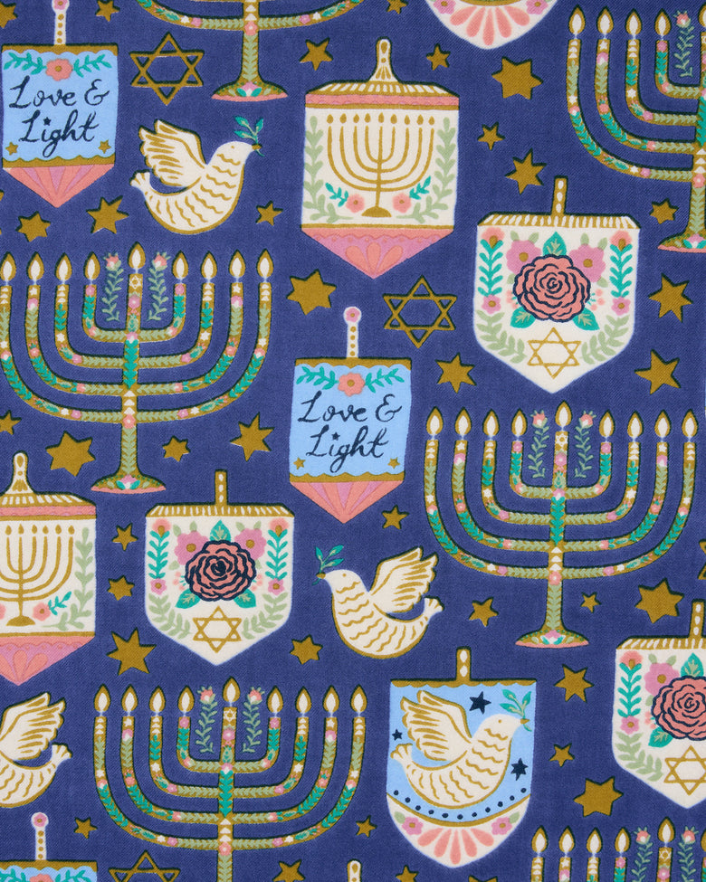 Hanukkah-themed blue apron print with repeating menorahs, stars, doves, dreidels, and menorah-shaped ornaments.