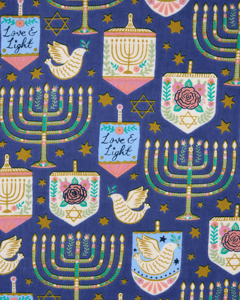 Hanukkah-themed blue apron print with repeating menorahs, stars, doves, dreidels, and menorah-shaped ornaments.
