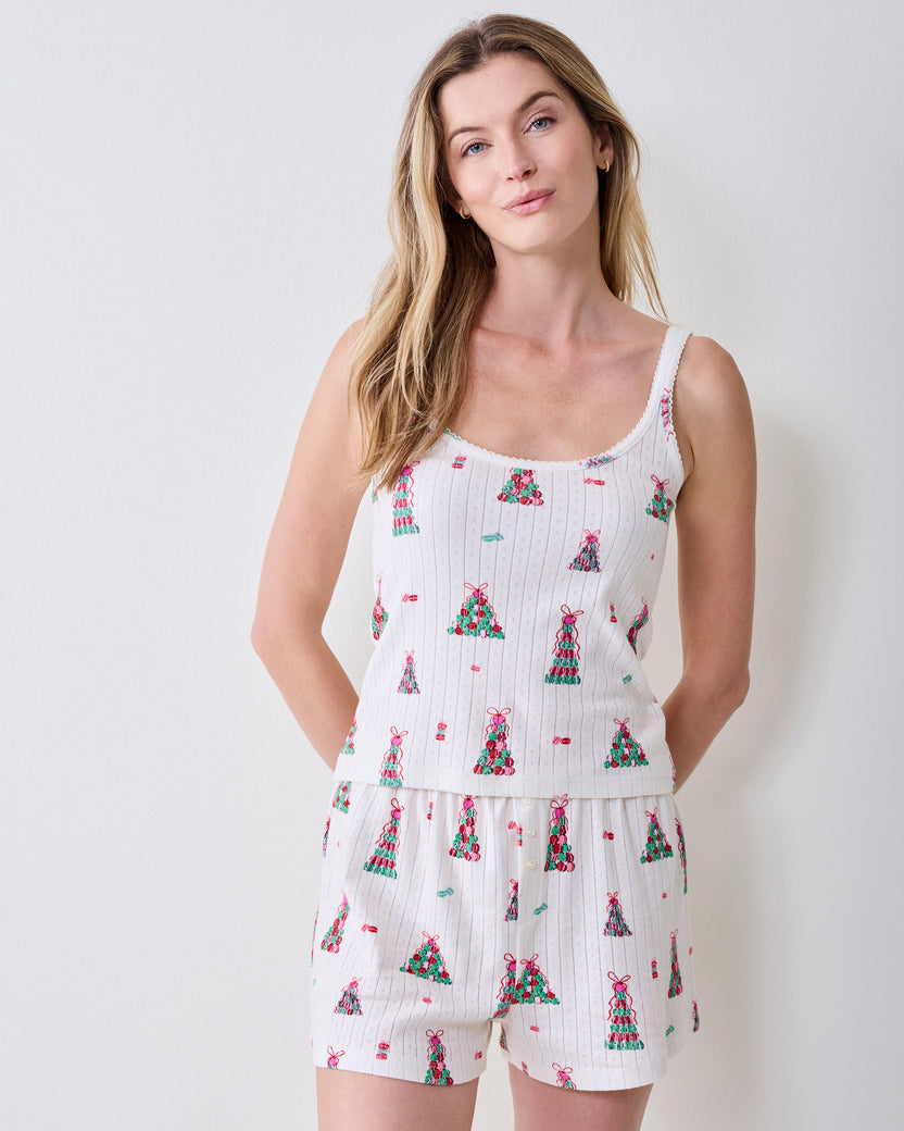 Person wearing a white camisole and matching shorts with a colorful Christmas tree print.