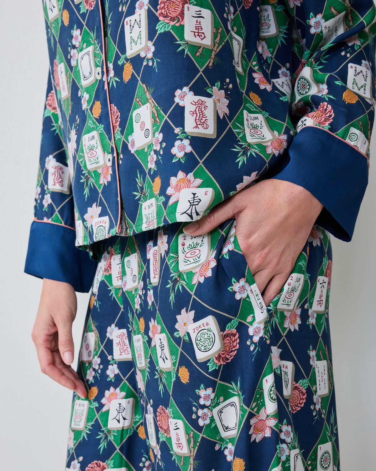 Close view of the Mahj Garden Wintergreen Eco Satin Soho pajama set, showing the patterned button-front top, cuff, and a hand in the matching pants pocket.