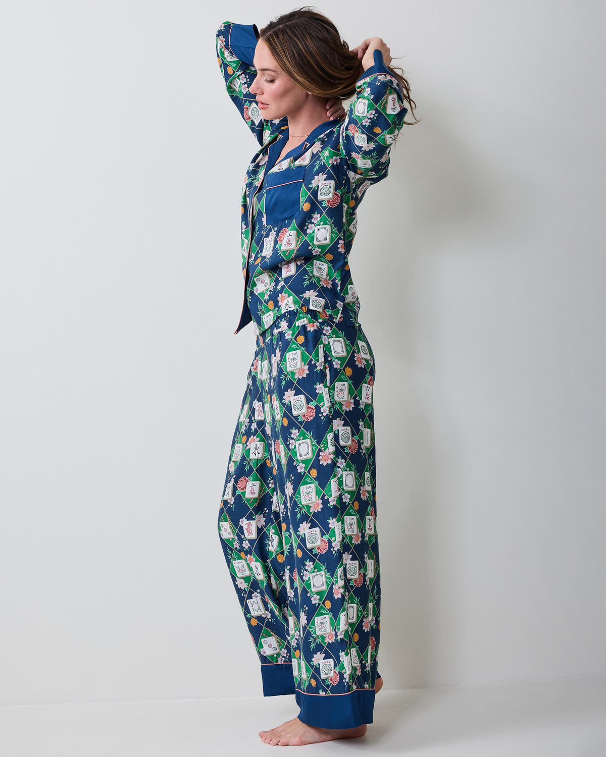 Full side view of a person wearing the Mahj Garden Wintergreen Eco Satin Soho pajama set, with a long-sleeved top and wide-leg pants.