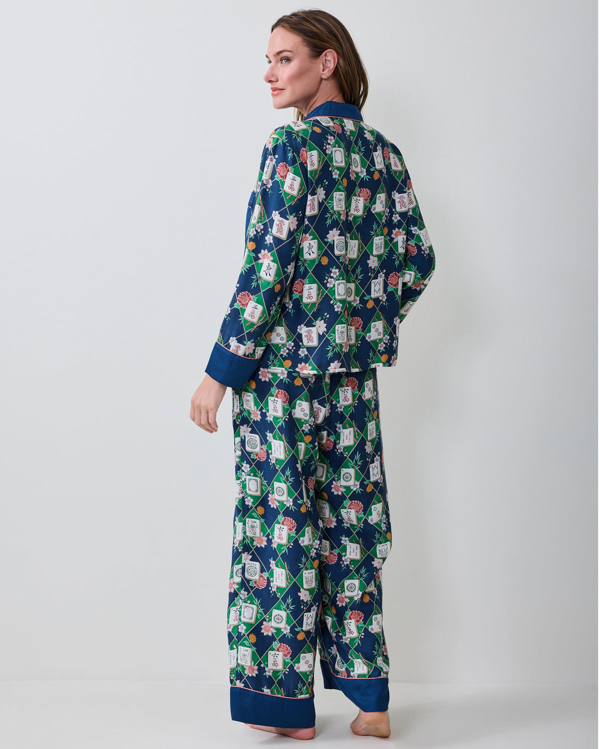 Three-quarter back view of a person wearing the Mahj Garden Wintergreen Eco Satin Soho pajama set, showing the patterned top and wide-leg pants.