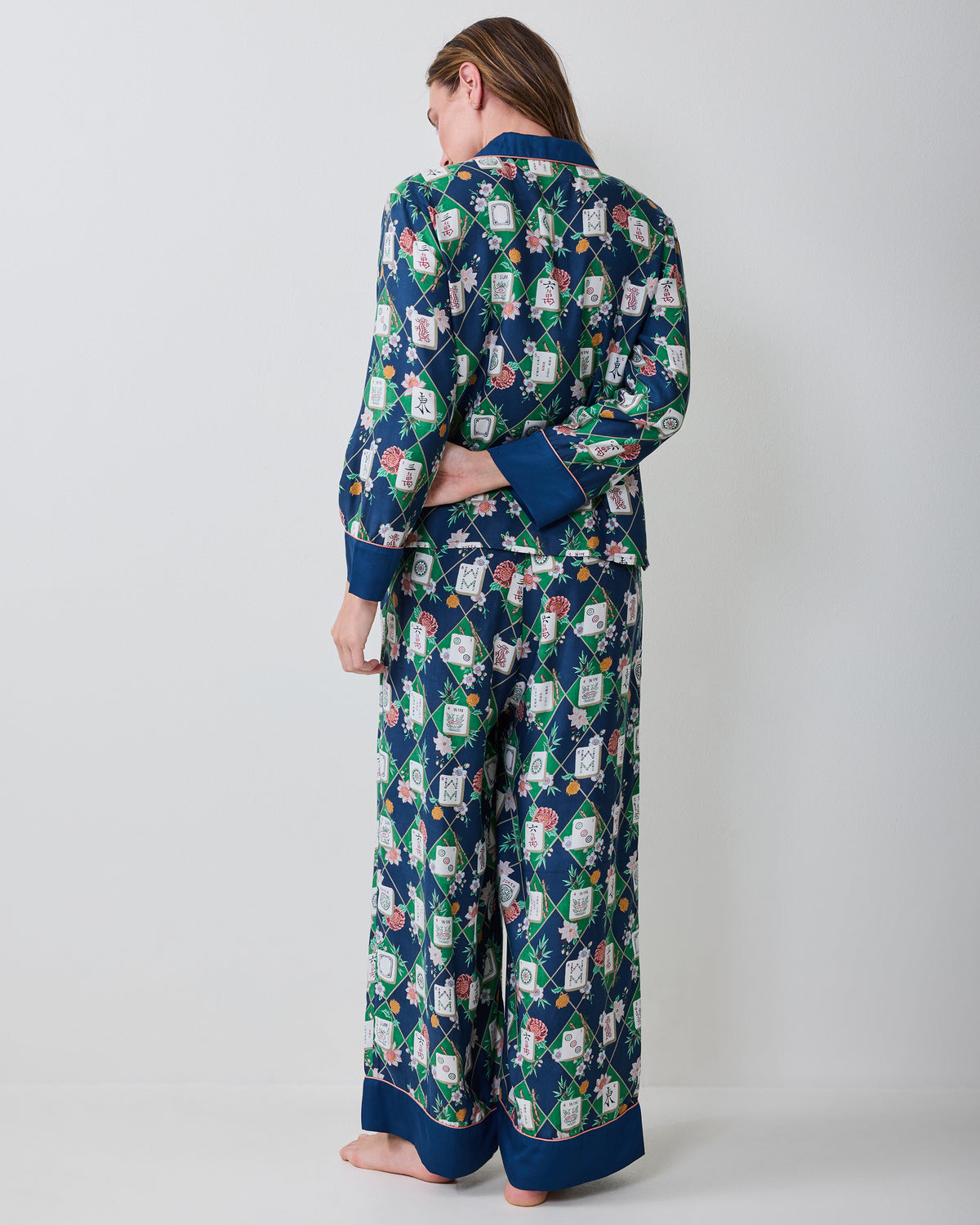 Back view of a person wearing the Mahj Garden Wintergreen Eco Satin Soho pajama set, showing the patterned top and matching wide-leg pants.