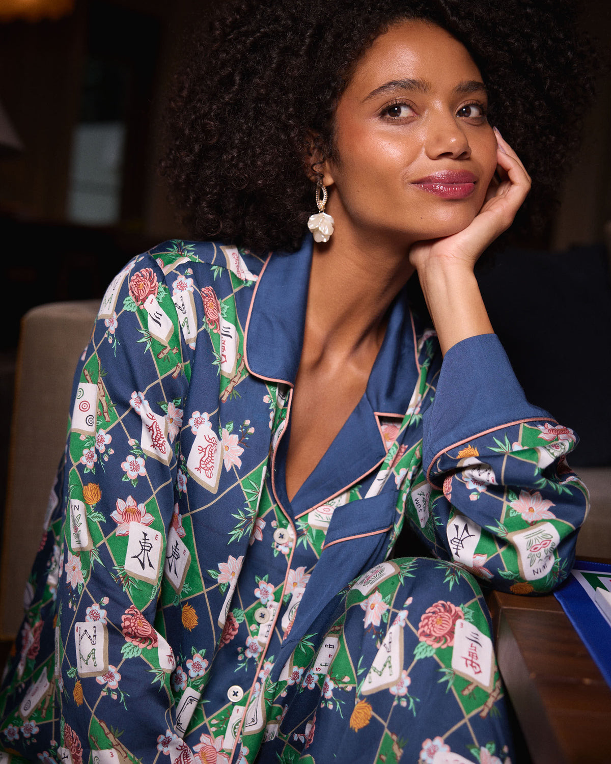 Close view of a person seated in the Mahj Garden Soho set, showing the patterned button-front top, contrasting collar and cuffs, and matching pants.