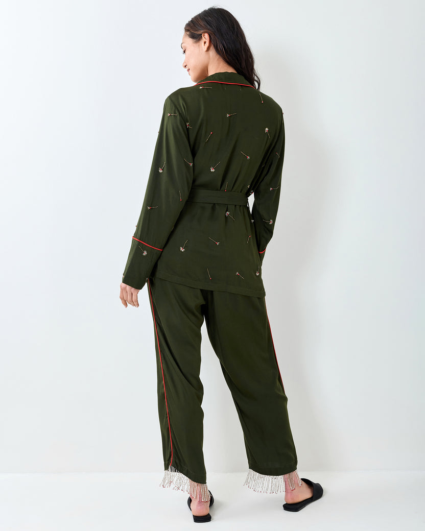 Back view of an olive long-sleeve top and matching pants with scattered embroidery, red piping, and beaded fringe at the pant cuffs.