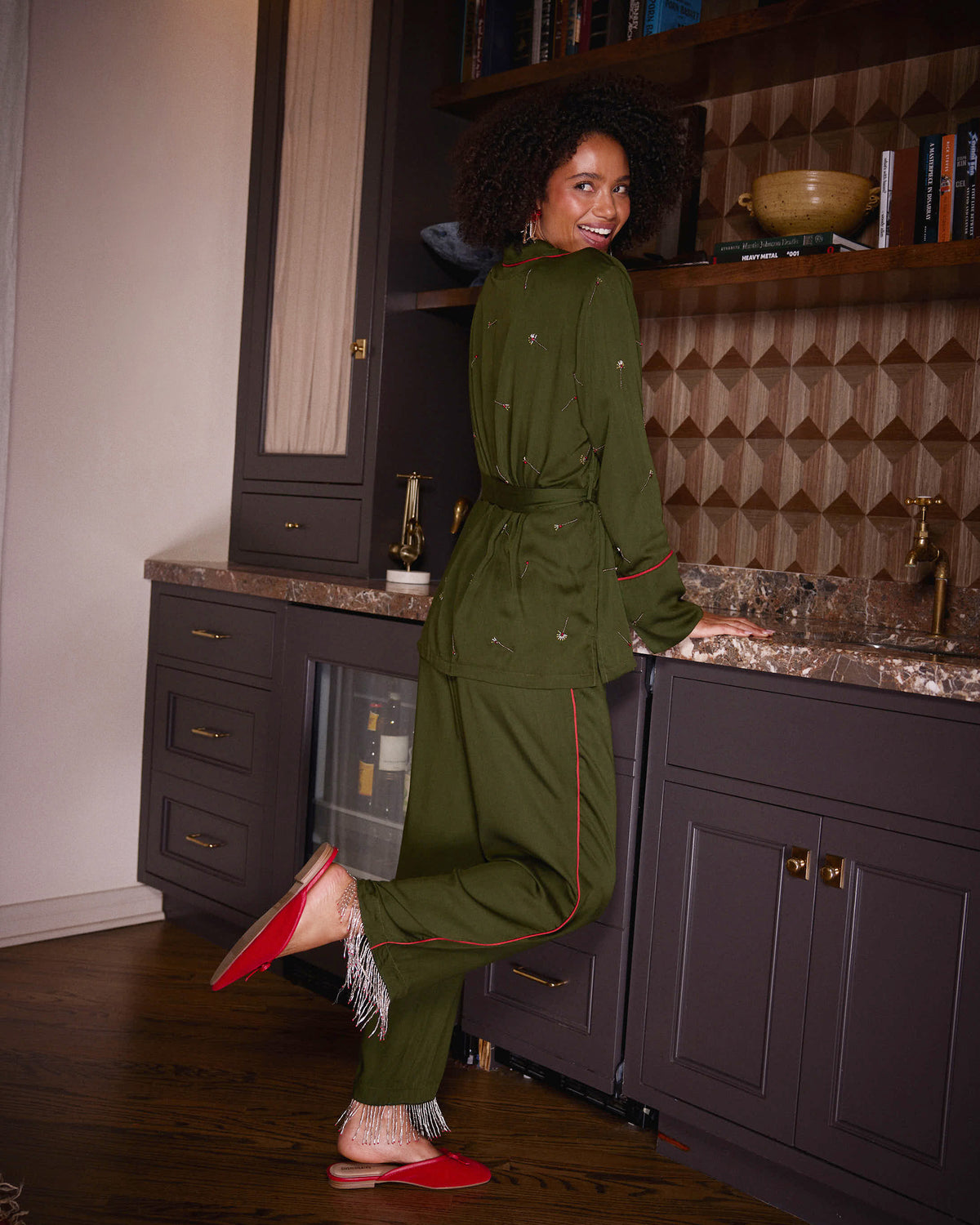 Back and side view of the olive Matchmaker pajama set, showing the belted top, straight-leg pants, red piping, and tassel-trimmed hems.