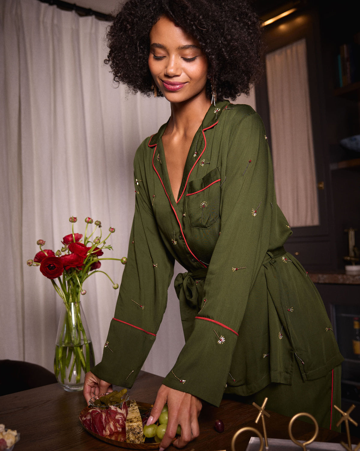 Front view of the olive Matchmaker belted pajama top with red piping, chest pocket, and small decorative motifs.