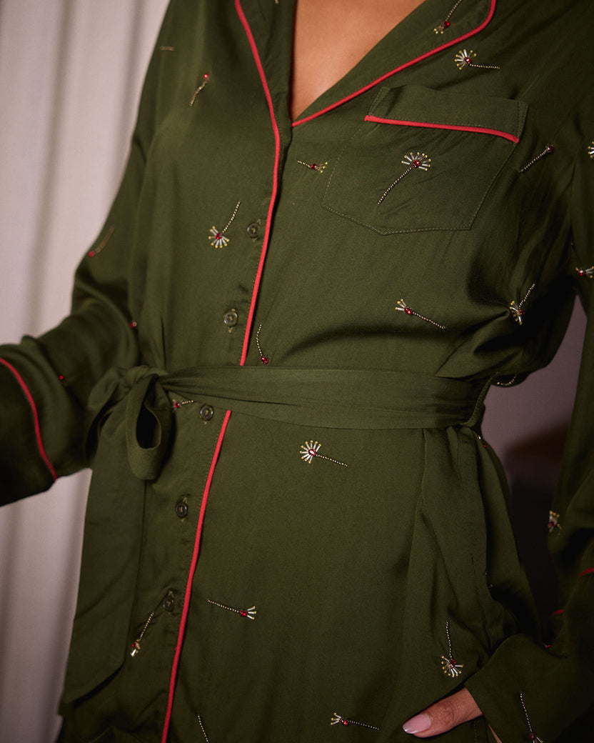 Close-up detail of the olive Matchmaker top showing red piping, buttons, chest pocket, waist belt, and decorative motifs.