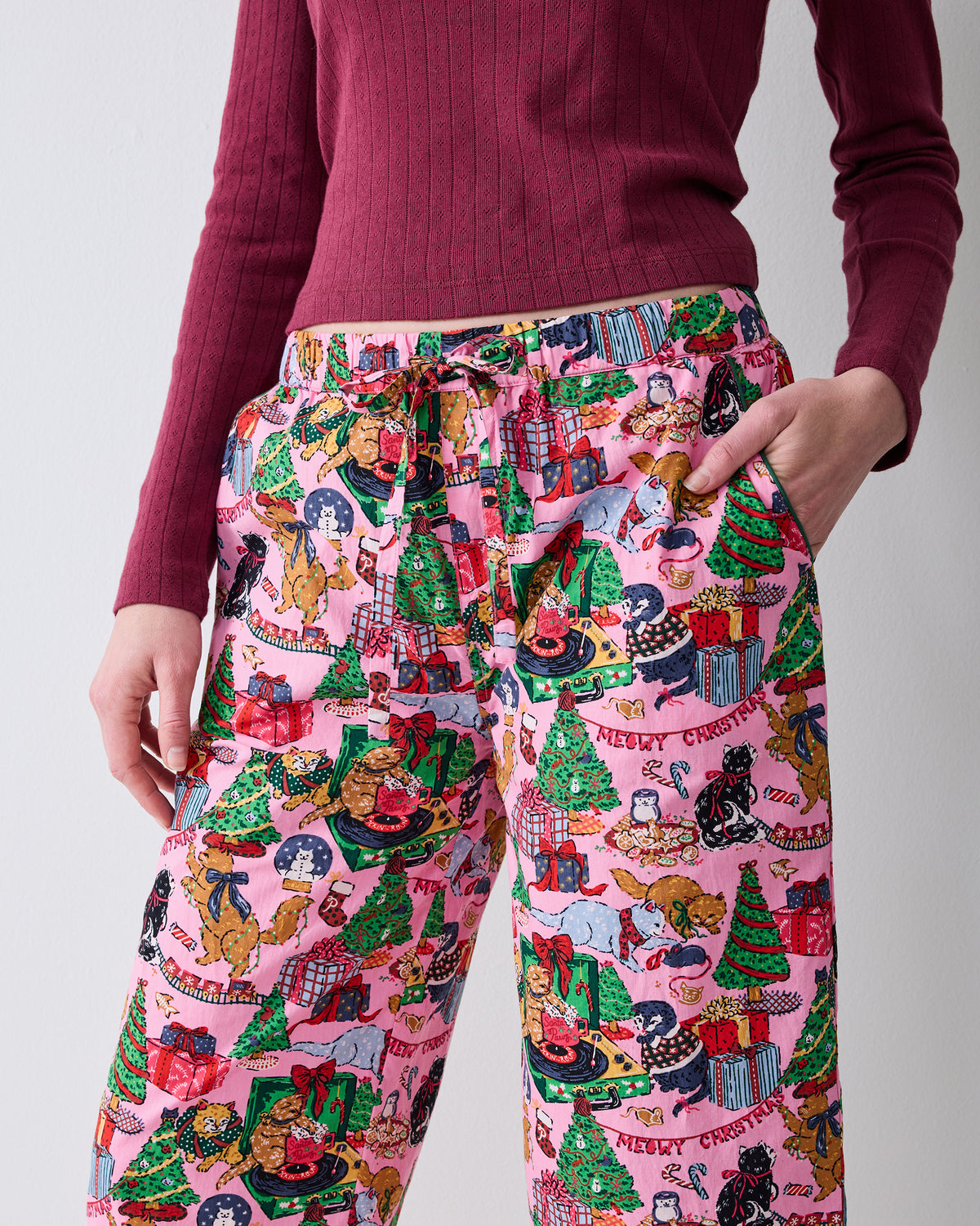 Close-up of the Candy Pink Meowy Christmas cropped pajama pants, showing the drawstring waist, side pockets, and printed design.