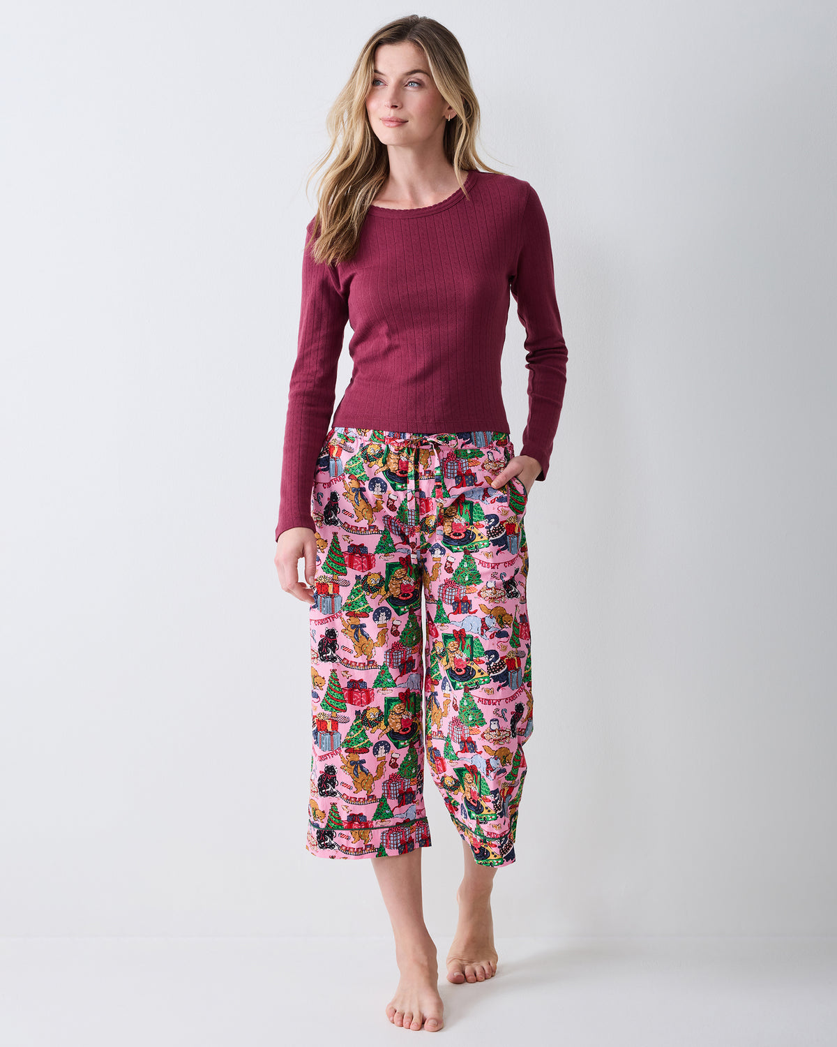 Front view of the Candy Pink Meowy Christmas cropped pajama pants, worn with a burgundy long-sleeve top.