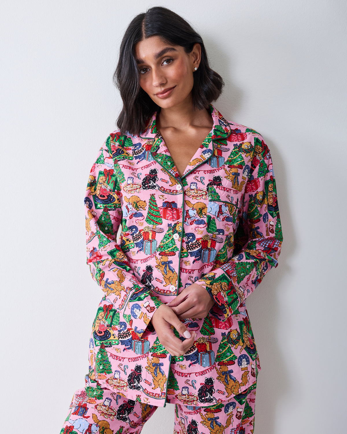Front view of a person wearing the candy pink long pajama set with a colorful Christmas cat-and-gifts print.