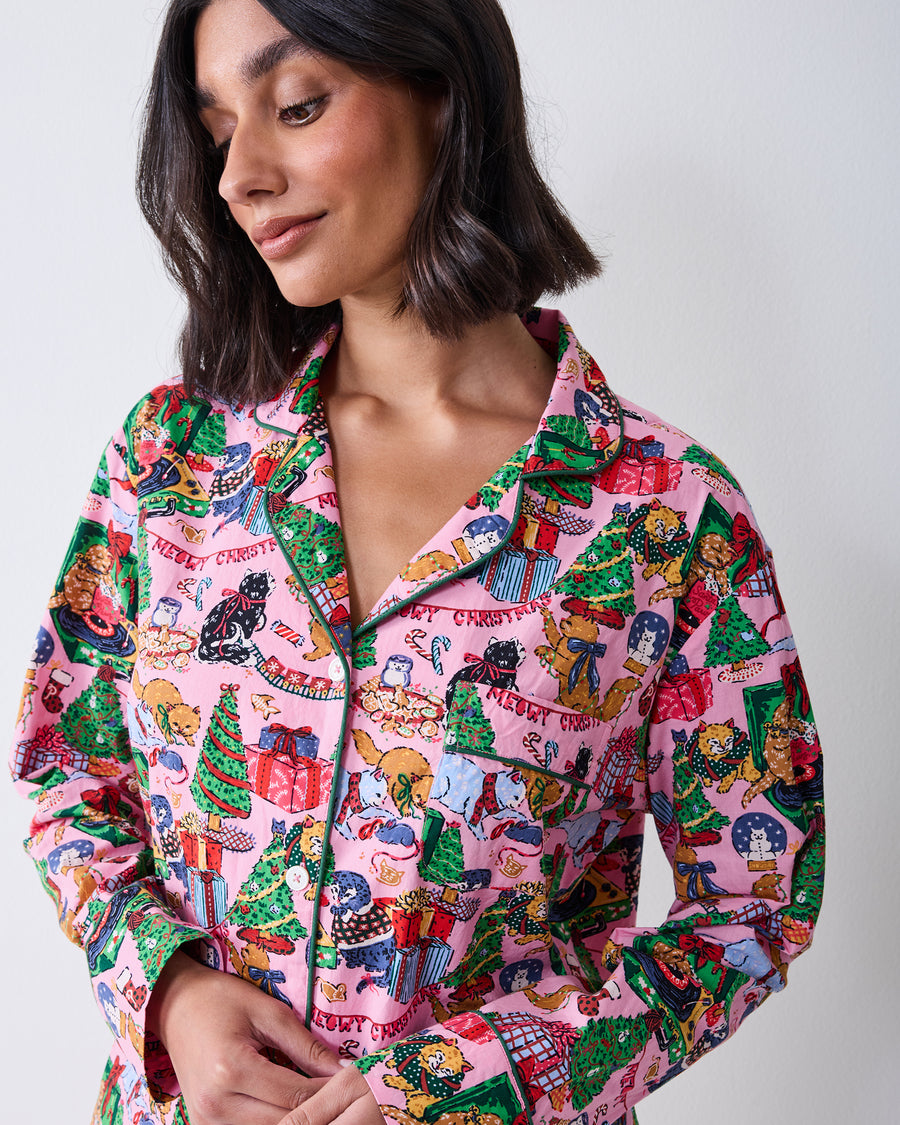 Close front view of the candy pink long pajama top, showing its green-trimmed collar, buttons, pocket, and Christmas cat print.