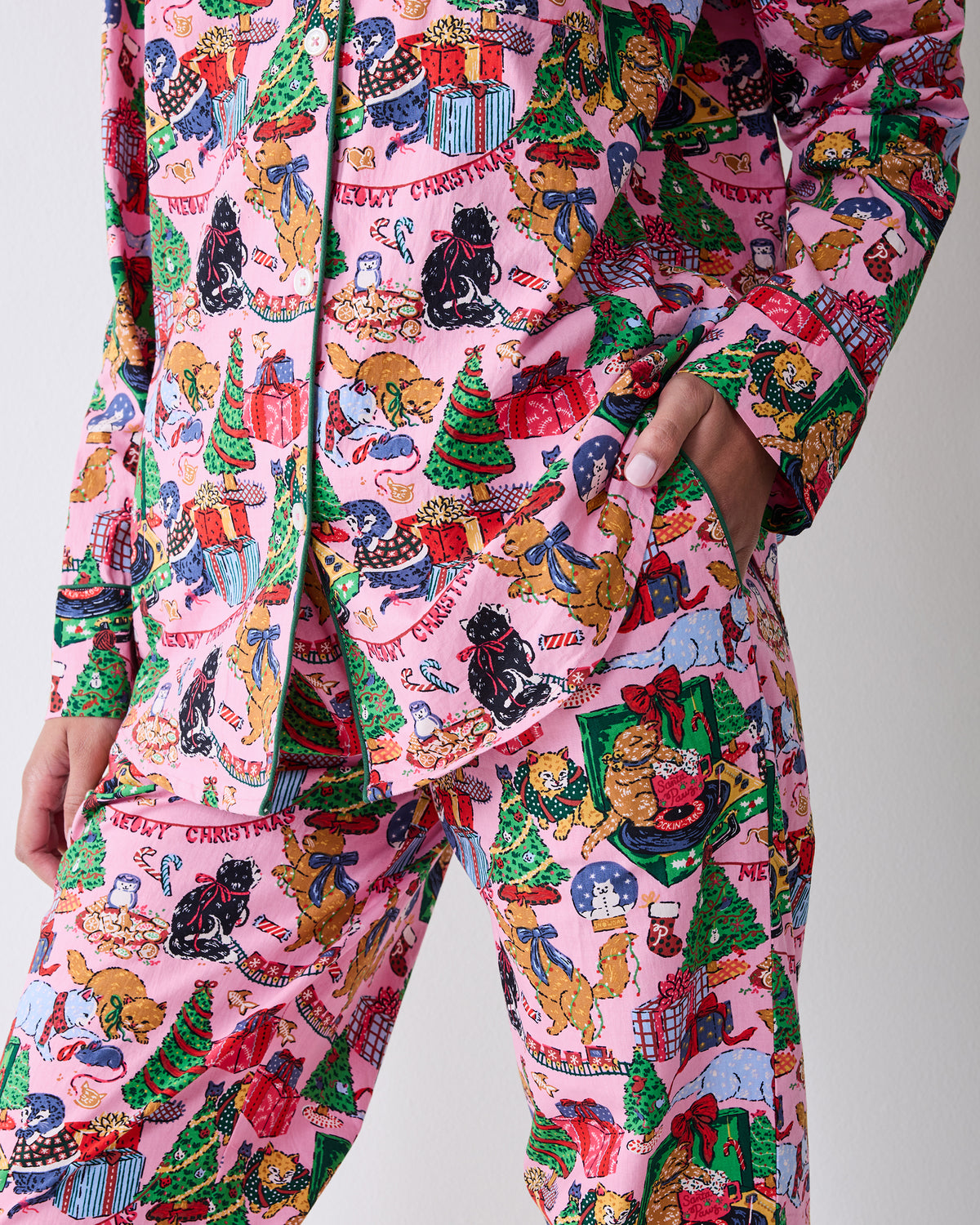 Close detail of the candy pink pajama set showing the button-front top, pocket, matching pants, and Christmas cat print.