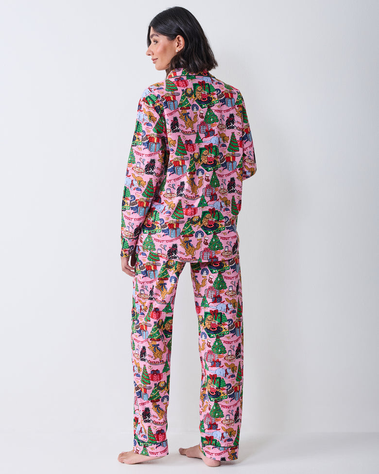 Back view of a person wearing the candy pink long pajama set with the Christmas cat, gift, and tree print across the top and pants.