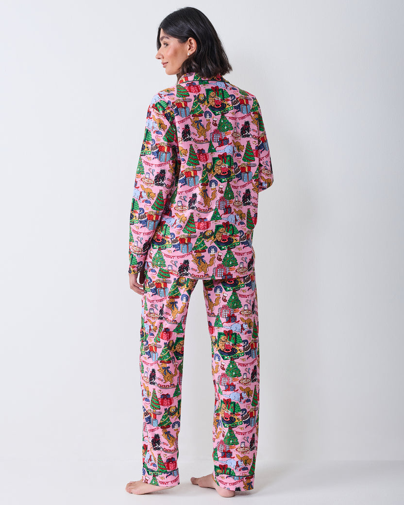 Back view of a person wearing the candy pink long pajama set with the Christmas cat, gift, and tree print across the top and pants.