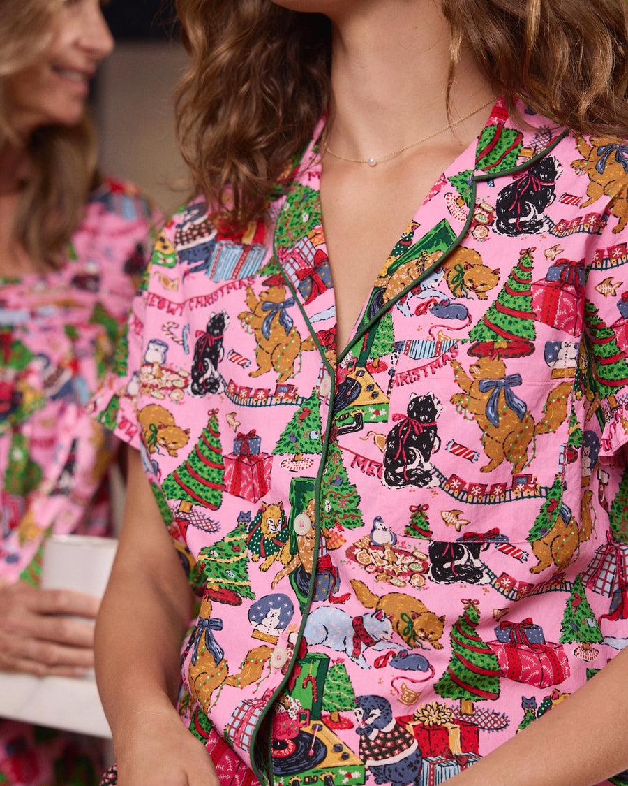 Close-up of the Candy Pink Meowy Christmas pajama top showing its green piping, buttons, and holiday cat print.