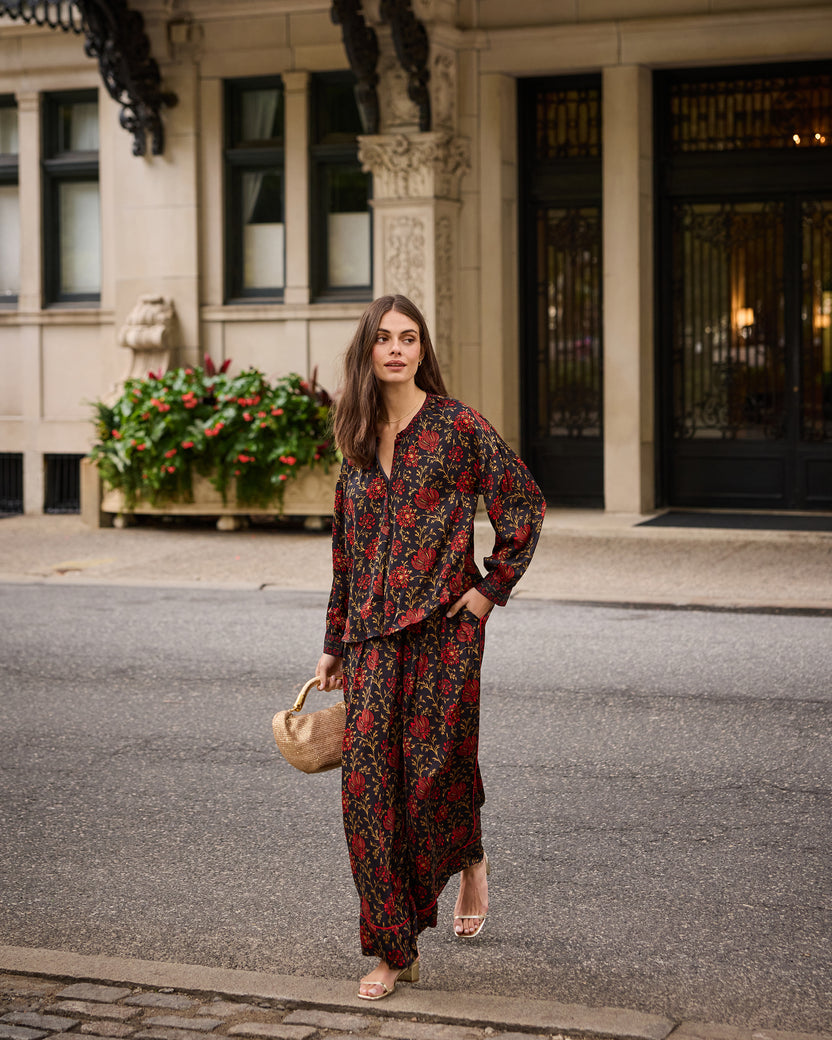 Full-length street view of the Midwinter Bloom Drew blouse worn with a matching long skirt and woven handbag.