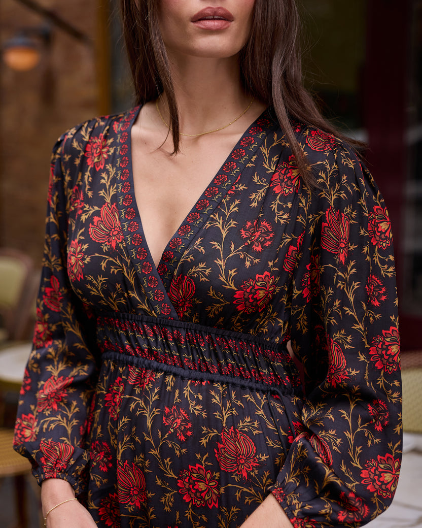 Close view of a person wearing a dark floral long-sleeved dress with a V-neck and gathered waist.