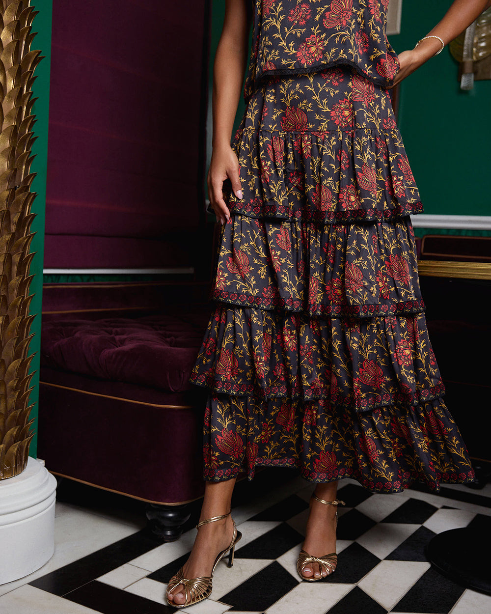 Close-up of the Noelle Set's tiered floral-print maxi skirt, with strappy sandals visible.