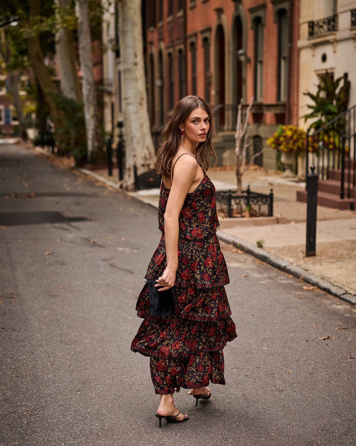 Model wearing the Midwinter Bloom Noelle set with a dark floral print on a residential street.