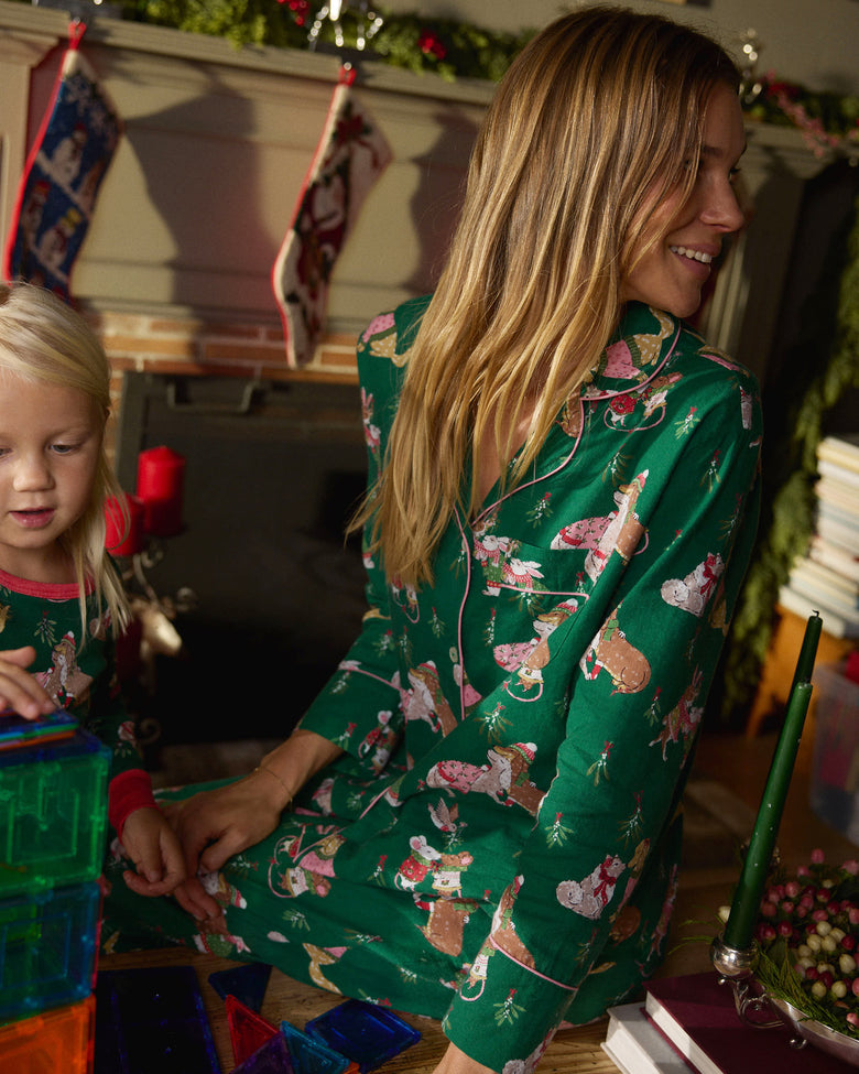 Side and back view of a person wearing the green Mistletoe Kiss flannel pajama set near a child in matching pajamas.