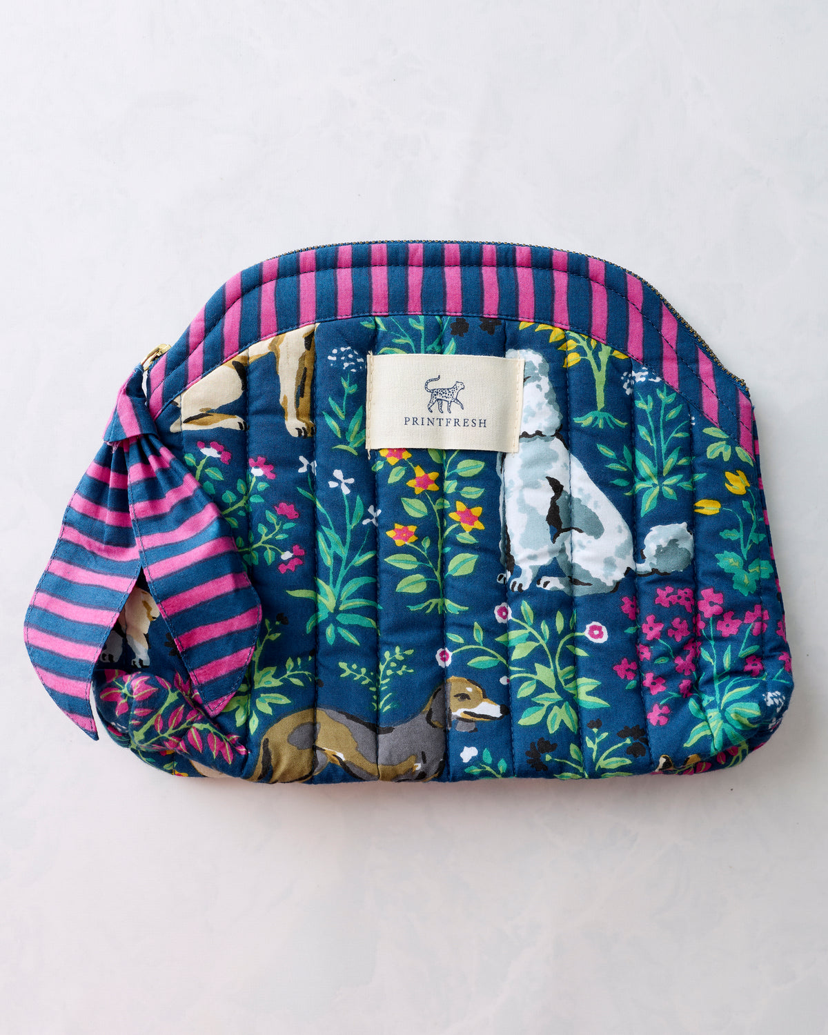 Indigo quilted Must Love Dogs makeup bag with rounded top, pink striped trim, zipper closure, and side tie.