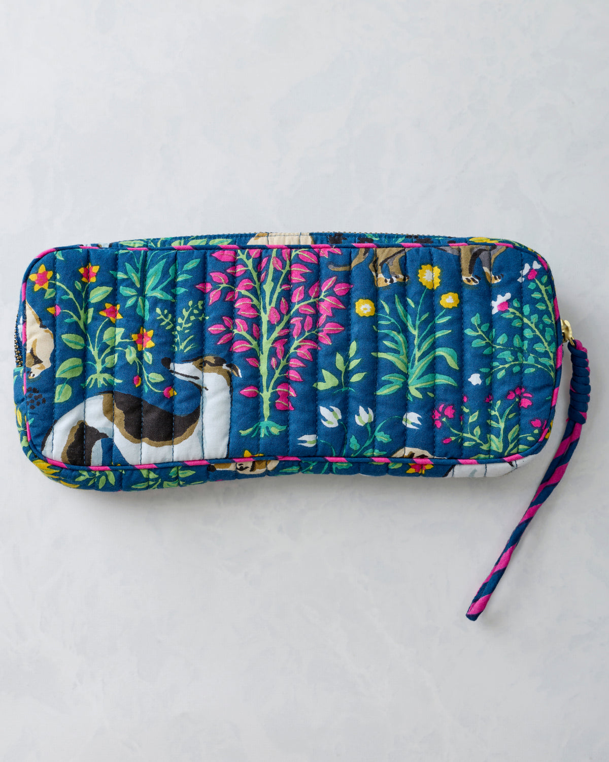 Reverse view of the quilted indigo sunglasses case showing its dog and floral print and wrist strap.
