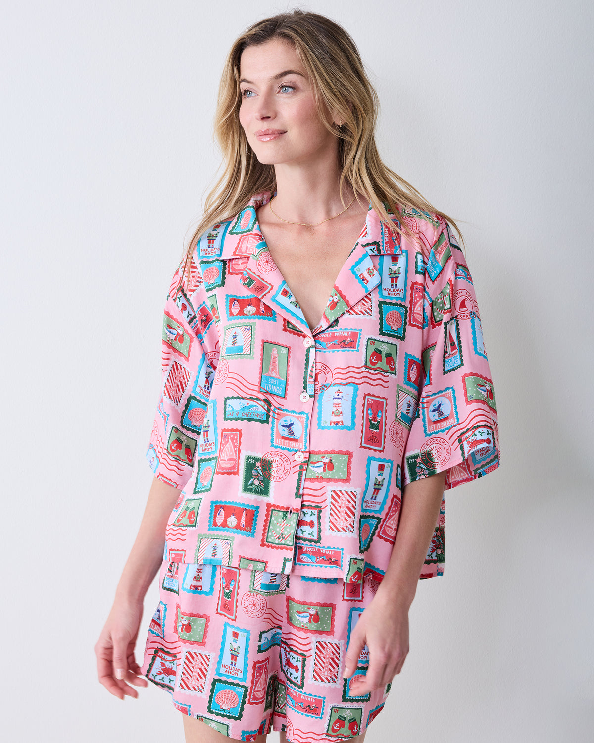 Front view of a person wearing the pink Nautical Stamps short pajama shirt and matching shorts.