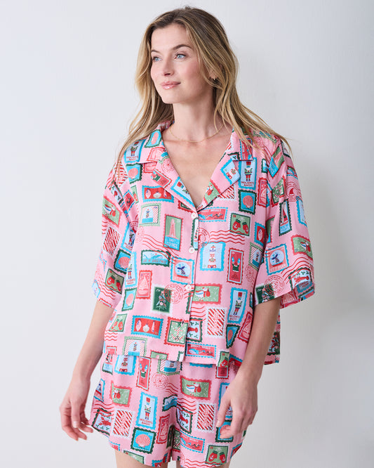 Front view of a person wearing the pink Nautical Stamps short pajama shirt and matching shorts.