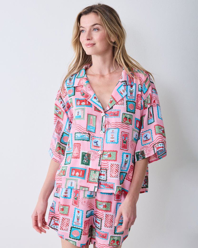 Front view of a person wearing the pink Nautical Stamps short pajama shirt and matching shorts.