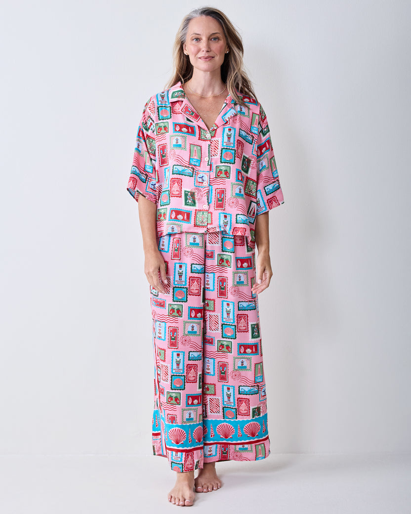 Full-length front view of a person wearing the pink Nautical Stamps long pajama set with a button-front top and straight-leg pants.