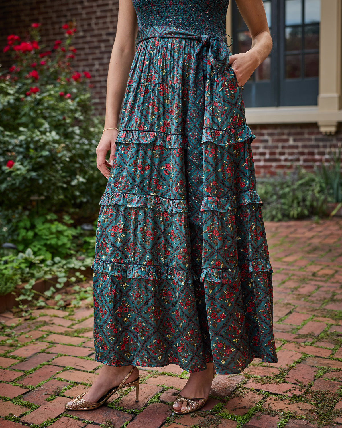 Close view of the Nordic Garden maxi dress showing its floral patterned fabric, tiered ruffles, tie waist, and side pockets.