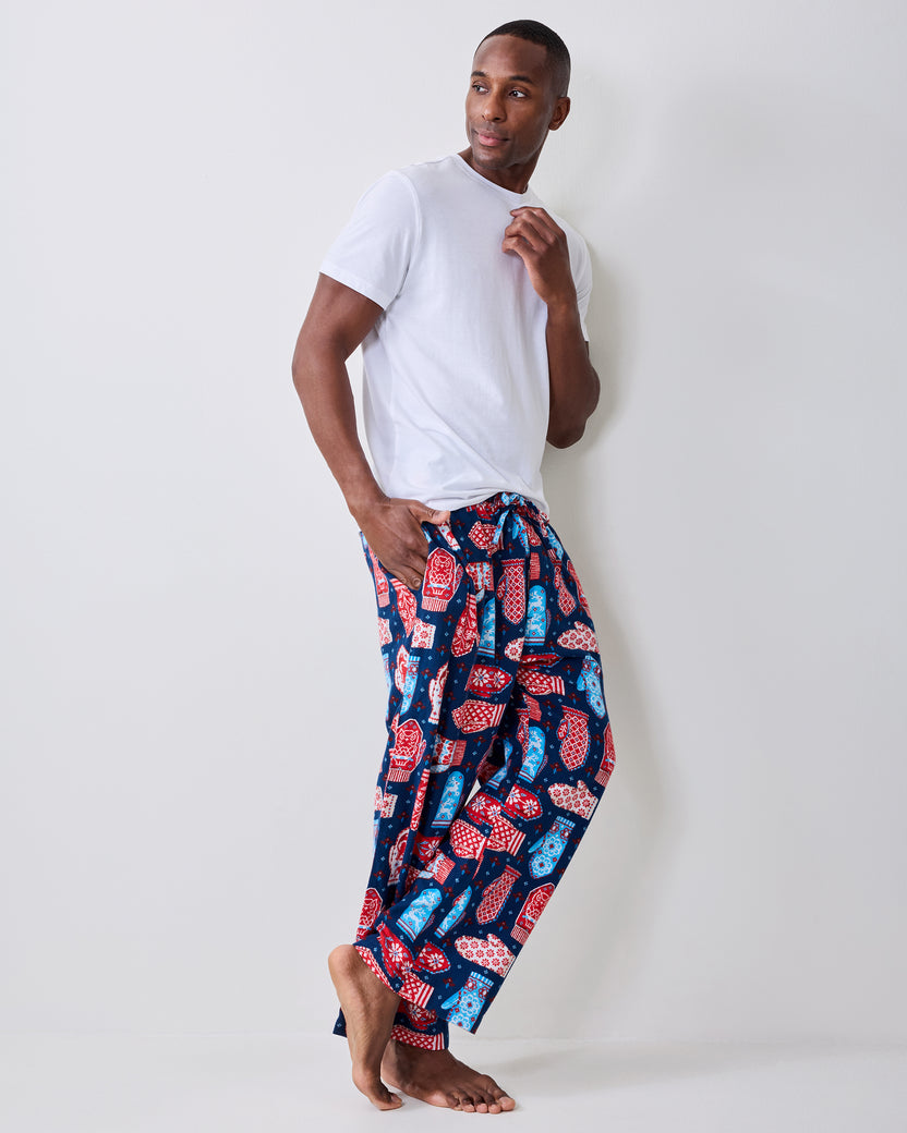 Side view of blue flannel men's pajama pants with a red, white, and light blue mitten print, worn with a white T-shirt.