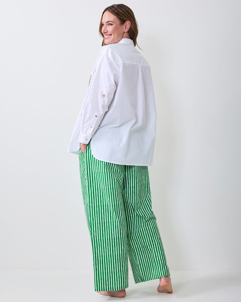 Back view of a white button-down shirt worn over green-and-white vertically striped pants.