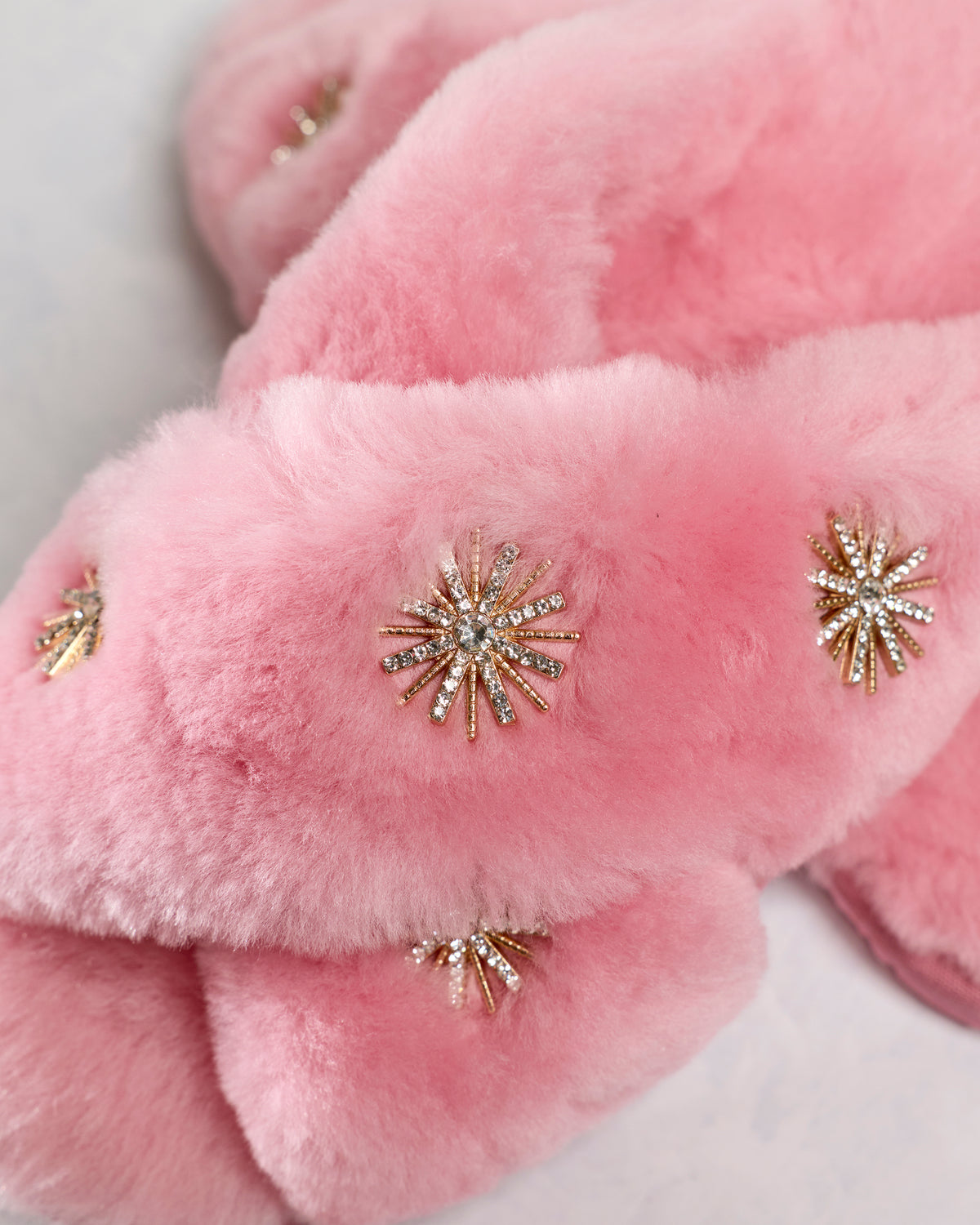 Close-up of pink slipper straps with rhinestone starburst embellishments.