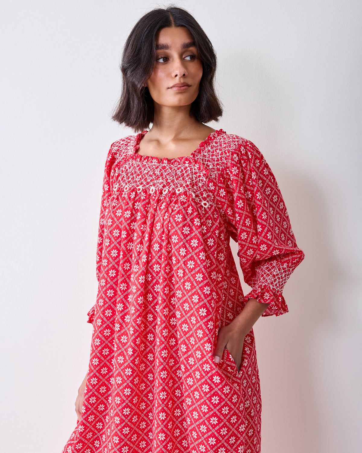 Front three-quarter view of the red patterned Parker nightgown, showing the gathered neckline, buttons, pockets, and sleeve details