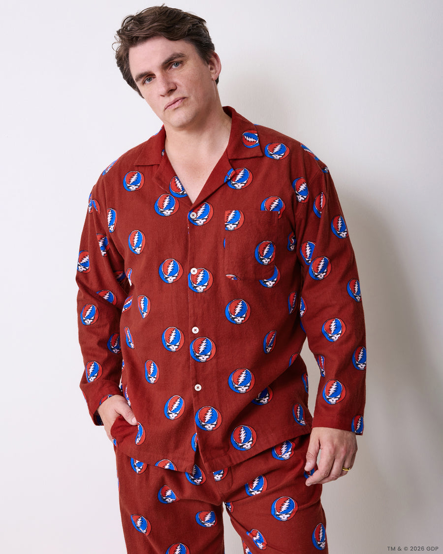 Full-length view of a person wearing a red long-sleeved pajama set with a repeating skull-and-lightning-bolt print.