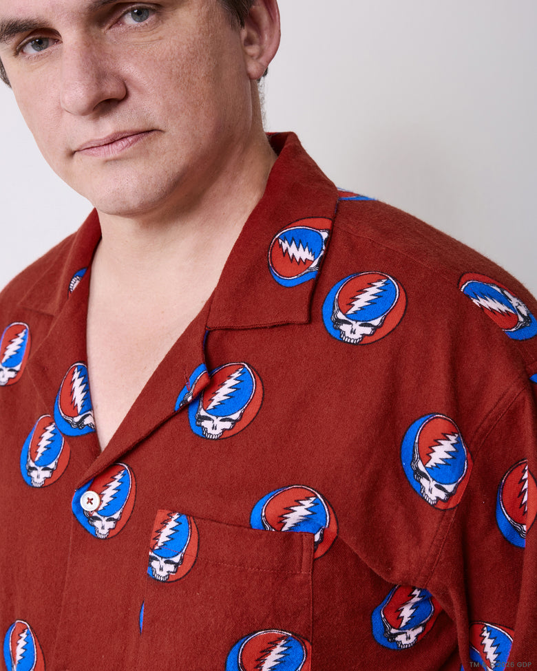 Close-up of the red pajama shirt showing the collar, shoulder, chest pocket, buttons, and skull-and-lightning-bolt print.