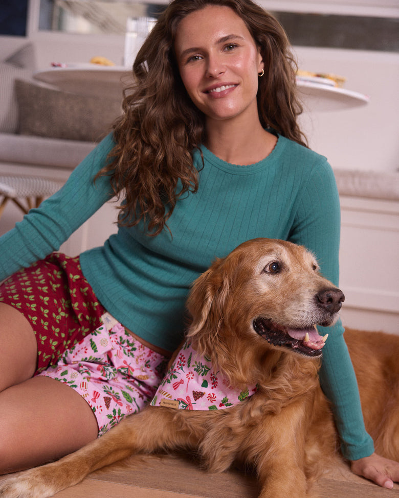 Person seated beside a golden retriever wearing a pink patterned pet bandana.