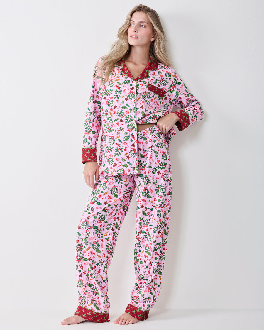 Full front view of a person wearing the Candy Pink Sweet Tooth long pajama set with red contrasting collar, cuffs, and ankle bands.